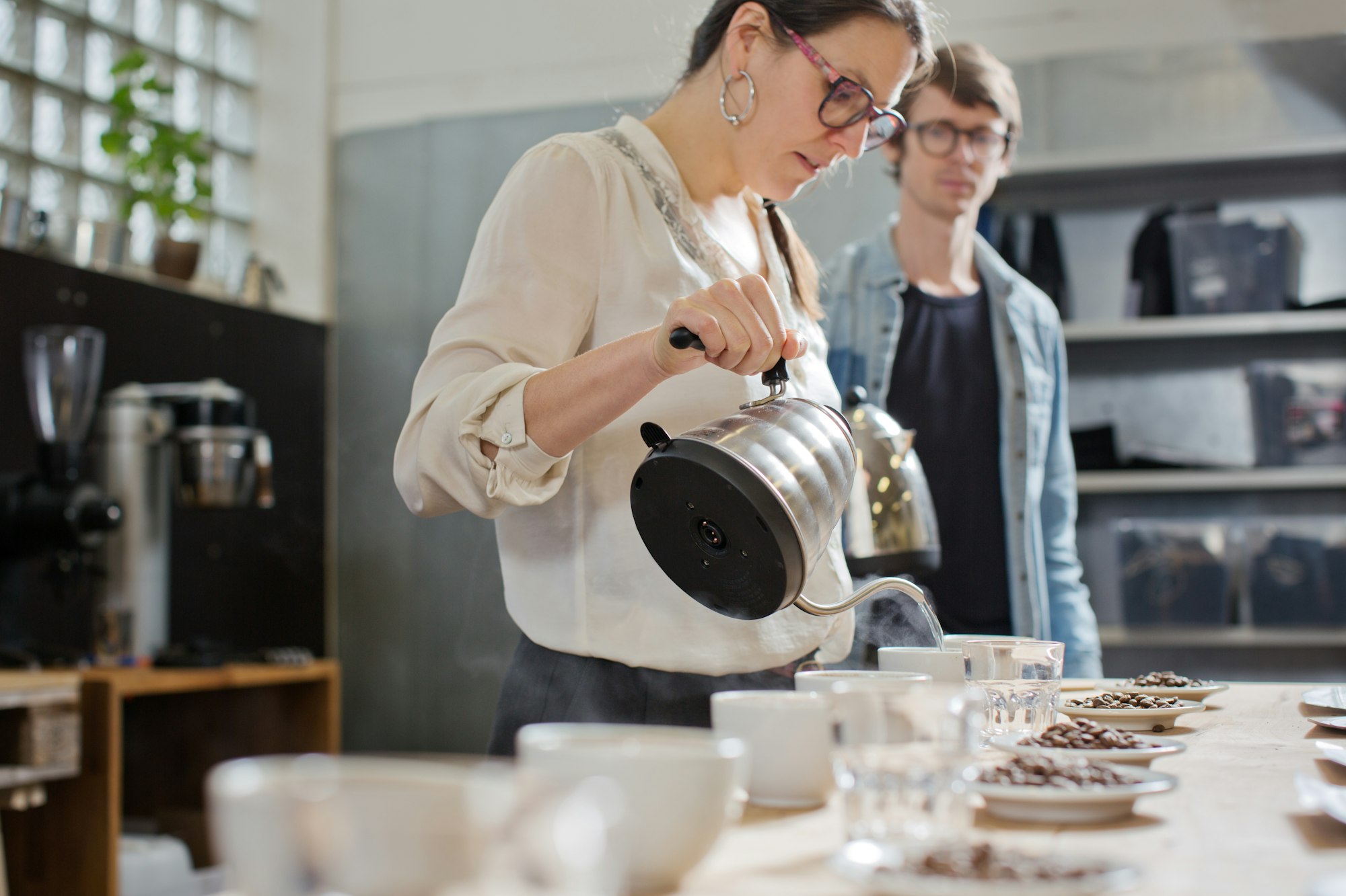 Coffee taster pouring hot water into cup of coffee